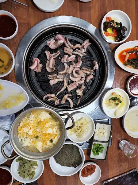 불판 위에서 익어가는 고기와 곁들임 음식들, 그리고 찌개