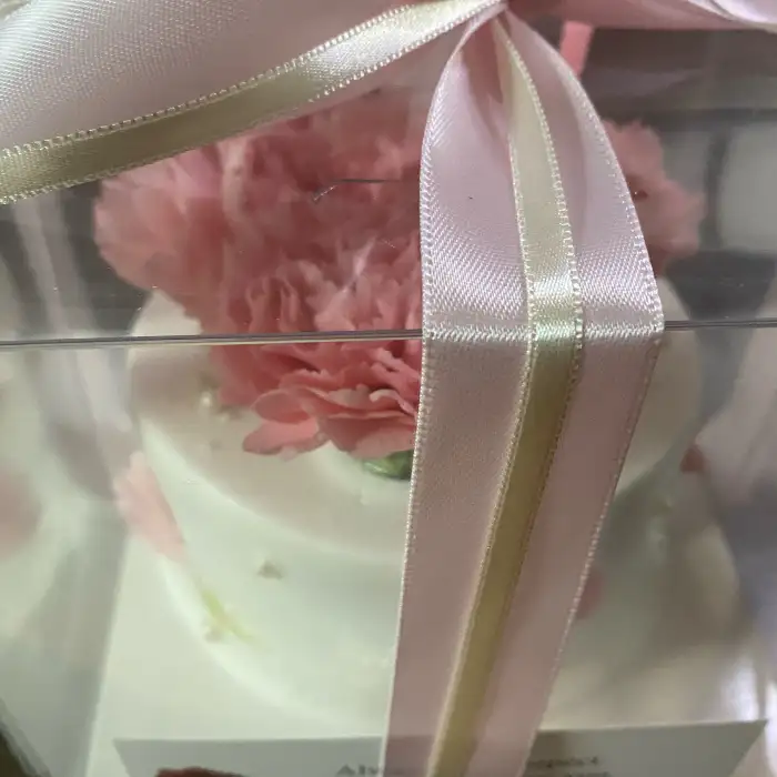 케이크를 감싸고 있는 투명 박스와 핑크색 리본