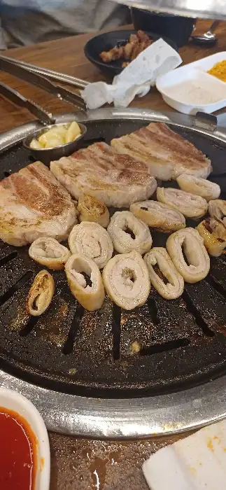두툼한 삼겹살과 동그란 모양의 막창이 숯불 위에서 익어가고 있는 모습
