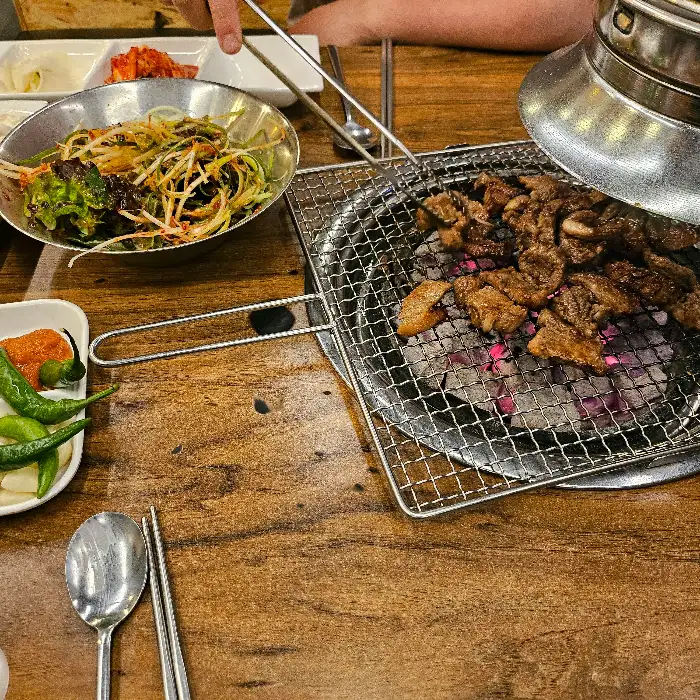 숯불 위에서 익어가고 있는 돼지갈비와 곁들임 샐러드