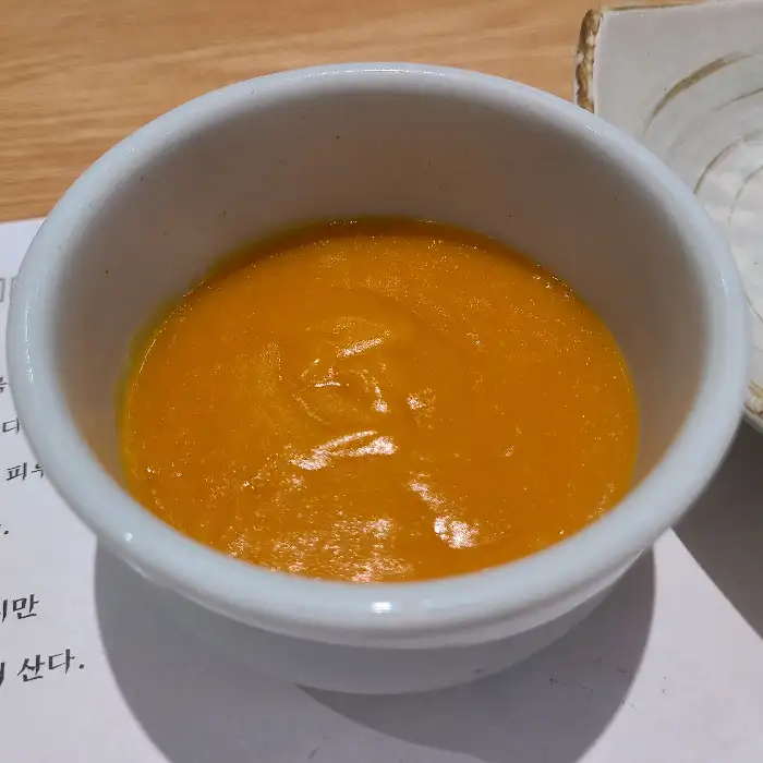 따뜻하고 부드러운 주황색의 단호박 퓨레가 담긴 흰색 그릇