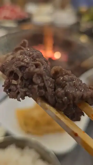 집게로 집어 올린 고기 한 점