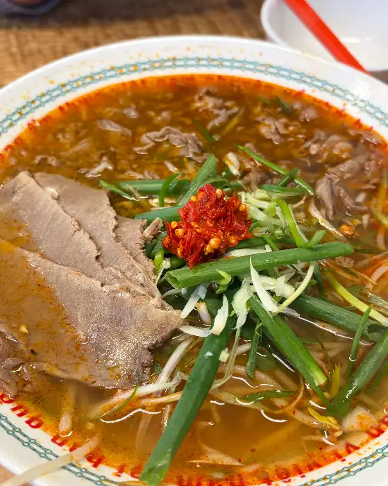 매콤한 쌀국수 위에 얹어진 붉은 소스와 고수