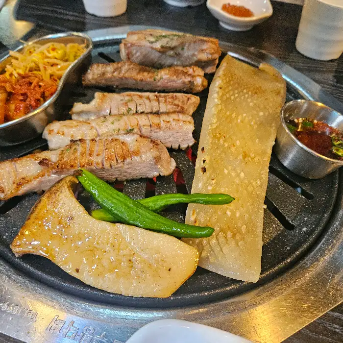 노릇하게 구워진 삼겹살과 목살이 불판 위에 놓여 있습니다.