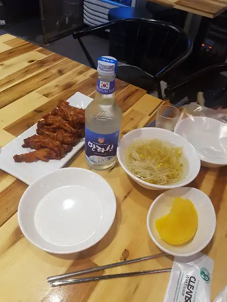 테이블에 놓인 닭발, 국물, 소주, 그리고 곁들임 반찬