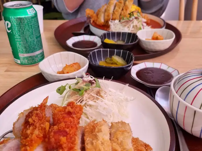 푸짐하게 차려진 돈까스 한 상과 음료수