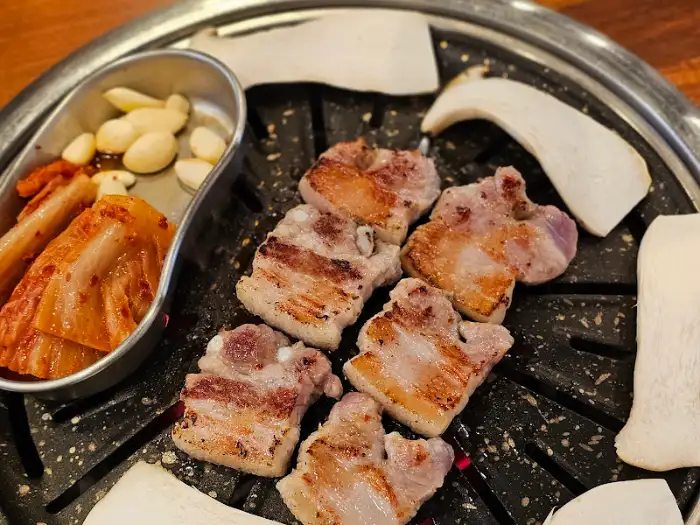 잘 익은 삼겹살 조각과 곁들여 나오는 김치, 마늘