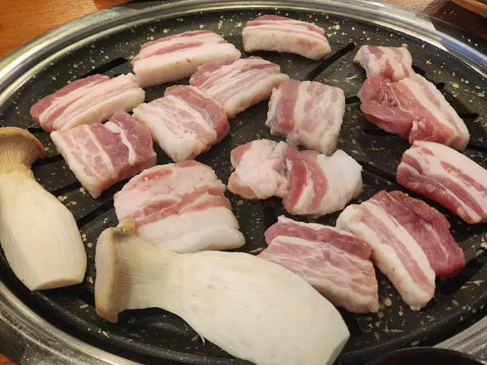 불판 위에서 익어가는 삼겹살과 버섯