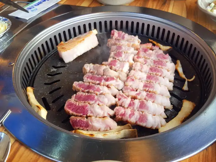 두툼한 삼겹살 덩어리가 불판에 올려져 익고 있는 모습