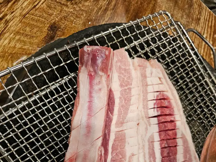 불판 위에서 구워지고 있는 두툼한 돼지고기. 지방과 살코기의 비율이 좋아 보인다.