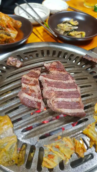 숯불 위에서 구워지고 있는 소고기 스테이크