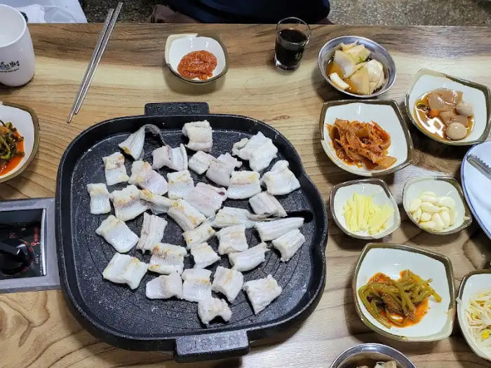 불판 위에 구워지는 장어와 다양한 밑반찬들