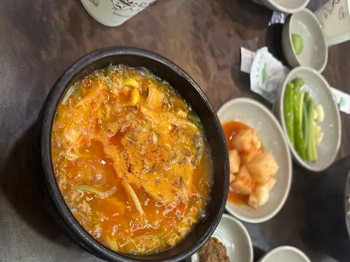 뚝배기에 담긴 얼큰한 국물의 해장국 모습입니다. 건더기가 풍성하게 들어 있습니다.