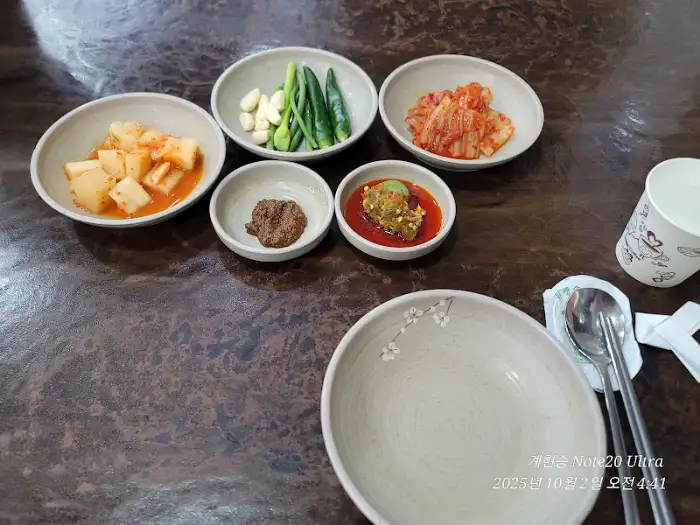 테이블 위에 다양한 종류의 김치와 쌈장, 그리고 양념장이 담긴 그릇들이 놓여 있습니다.