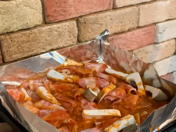 팬 위에서 익어가고 있는 양념 대패 삼겹살과 버섯.