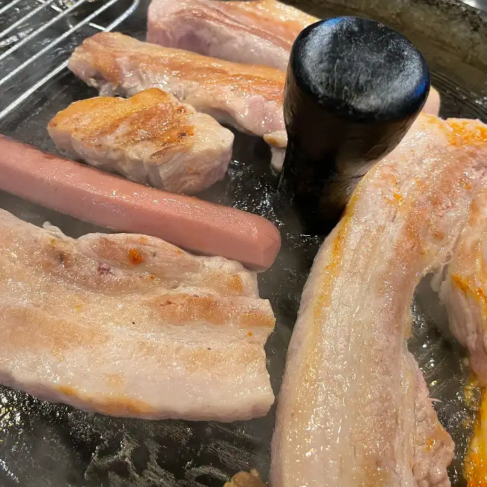 솥뚜껑 위에서 익어가는 삼겹살과 김치, 꽈리고추