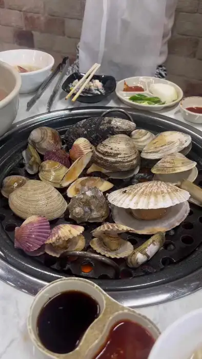 다양한 크기와 종류의 조개가 숯불판 가득 채워져 있는 모습