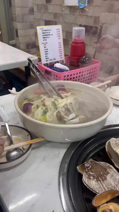 김이 모락모락 나는 커다란 탕 안에 면과 조개가 푸짐하게 들어있는 모습