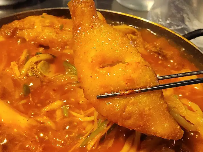 뜨겁게 끓고 있는 닭볶음탕 냄비 속 튀겨진 닭고기 조각