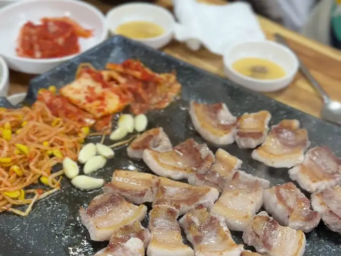 불판 위 삼겹살과 곁들임 채소