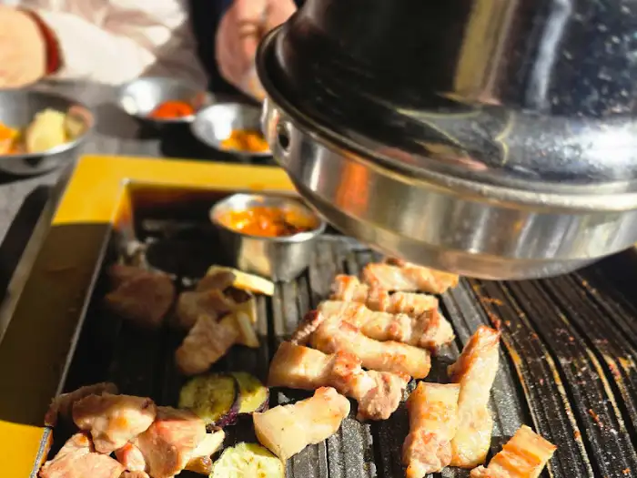 불판 위에서 맛있게 익어가고 있는 흑돼지와 곁들임 메뉴