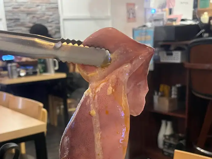 사장님이 집게로 들어 보여주는 신선한 오징어