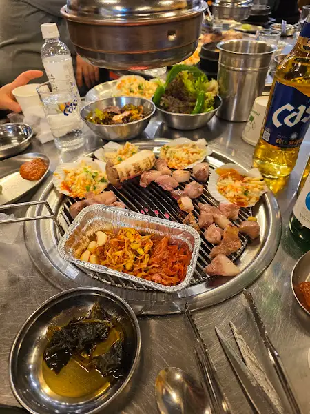 연탄 불판 위에 구워지고 있는 돼지고기와 곁들임 재료들