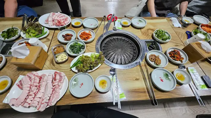 테이블에 차려진 다양한 밑반찬과 삼겹살