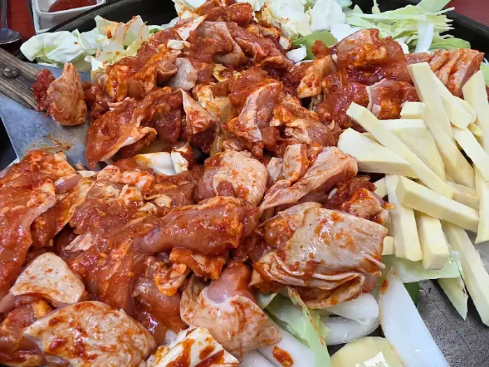 철판에 담긴 닭갈비 재료, 닭고기, 양배추, 떡, 우동 사리