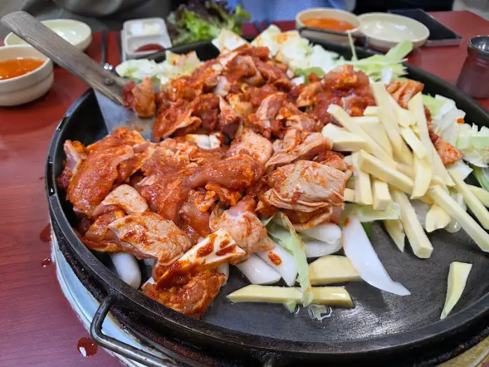 철판에 담긴 닭갈비 재료, 닭고기, 양배추, 떡, 우동 사리