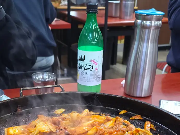 테이블 위에 놓인 녹색 소주병과 쇠 물병