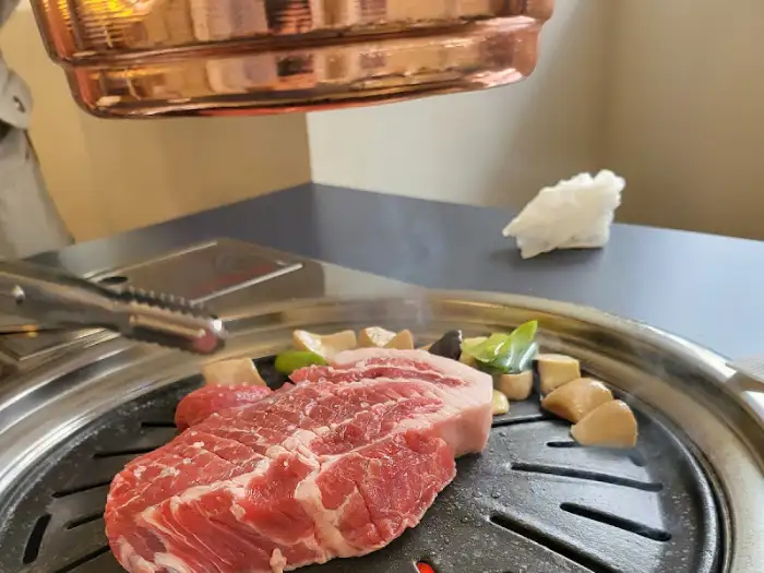 두툼한 통목살 한 점이 불판 위에서 익고 있는 모습
