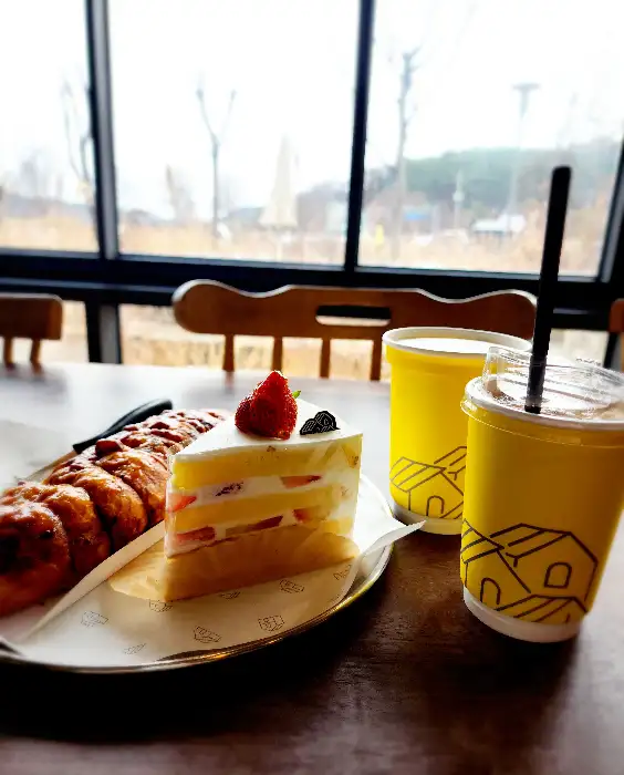 창가 테이블에 놓인 케이크, 빵, 음료 사진