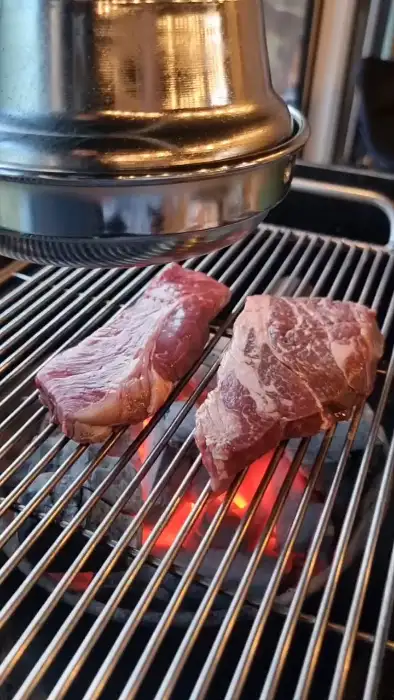 숯불 위에서 익어가는 두툼한 고기 덩어리
