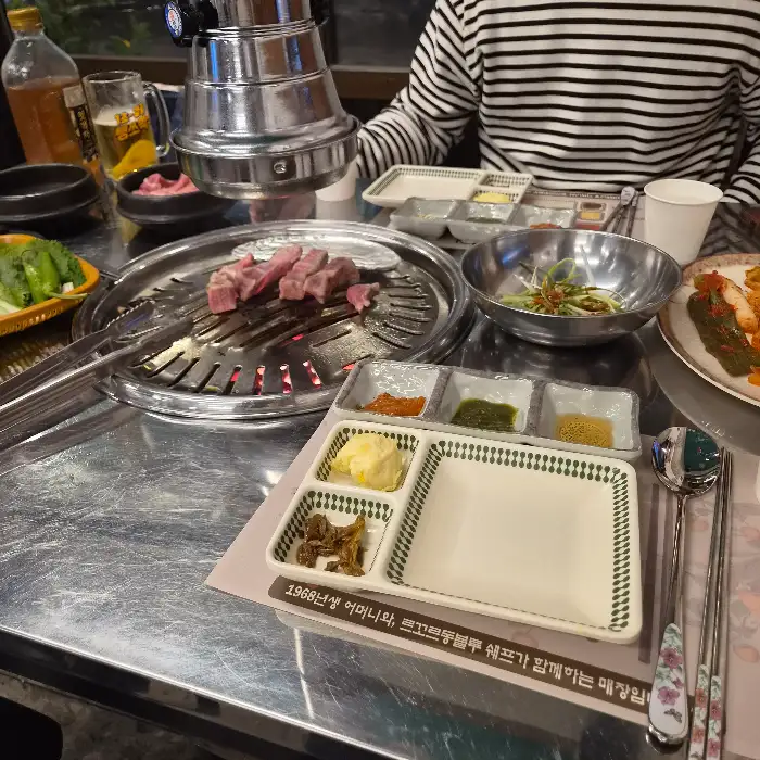 테이블에 놓인 연탄 불판과 고기, 그리고 다양한 쌈장들.