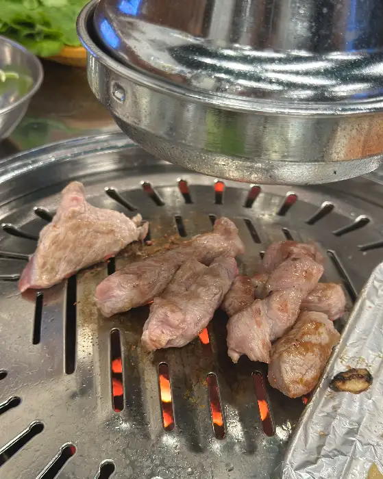 잘 익은 고기를 집게로 집어 올리는 모습.