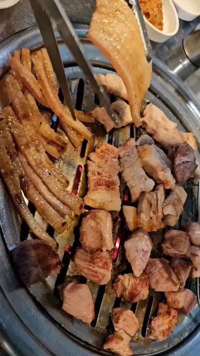 불판 위에서 구워지고 있는 다양한 종류의 고기와 쫄깃한 껍데기