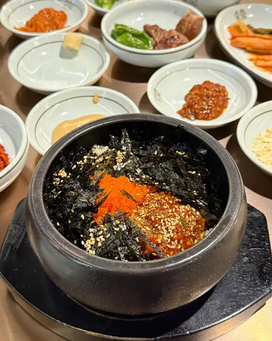 돌솥밥 위에 김가루와 붉은 소스가 얹어진 모습