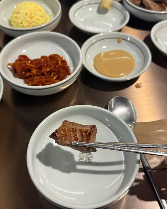 집게로 집은 잘 구워진 고기 조각