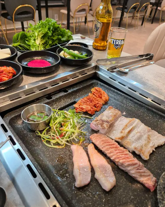 여러 종류의 고기와 쌈 채소가 준비된 불판