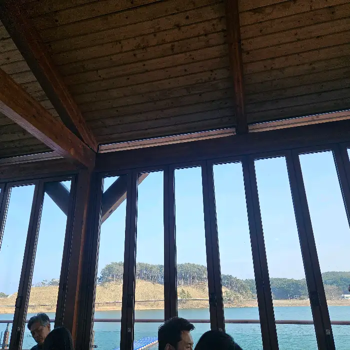 창밖으로 보이는 푸른 하늘과 나무, 그리고 잔잔한 호수 풍경