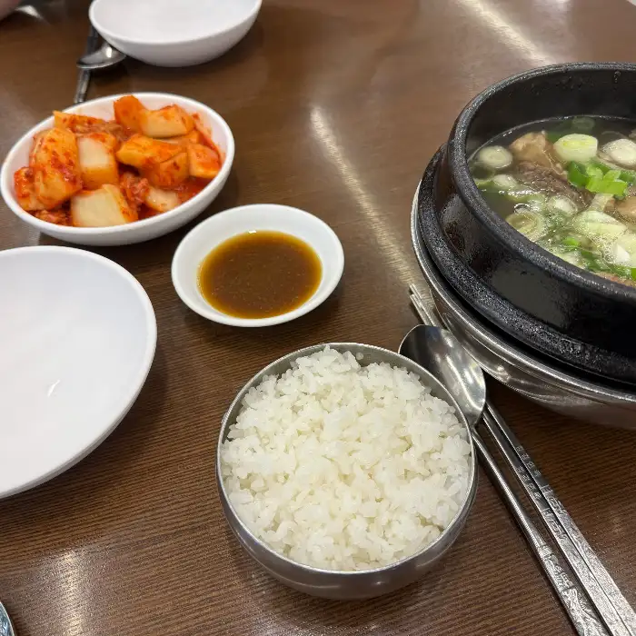 테이블에 차려진 따뜻한 갈비탕과 밥, 그리고 김치