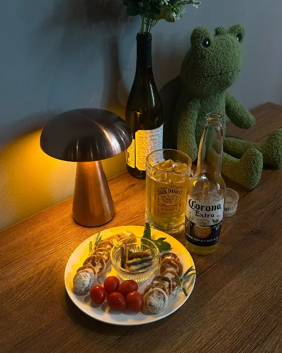 작은 버섯 모양의 조명과 함께 놓인 맥주와 간단한 안주