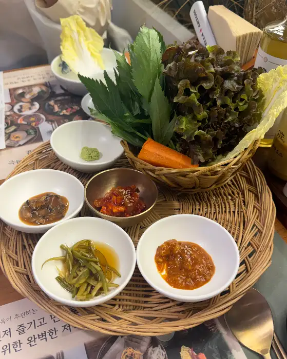 다양한 곁들임 찬과 신선한 채소들이 준비된 모습