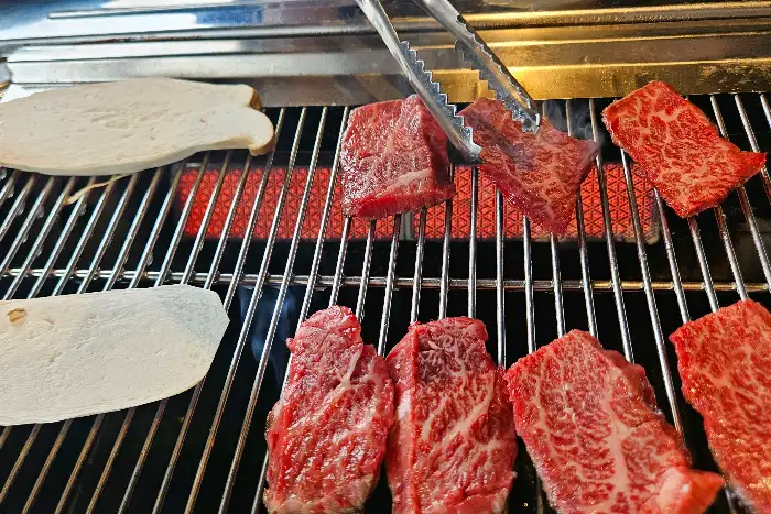숯불 위에서 맛있게 익어가는 투뿔 한우와 곁들임 버섯