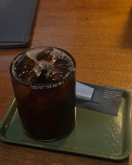 에메랄드색 쟁반 위에 놓인 얼음 가득한 아이스 커피 잔