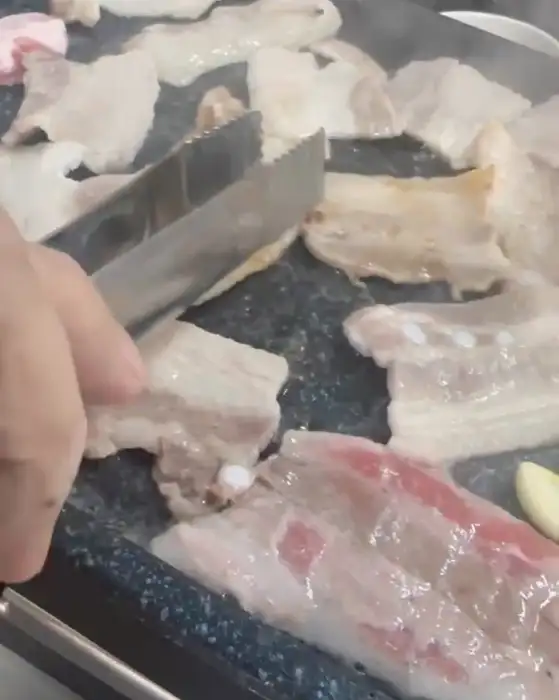 집게로 집어 맛있게 익은 삼겹살 조각