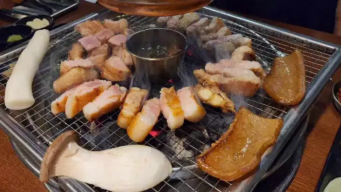 다양한 고기와 버섯, 떡 등이 불판 위에서 익고 있는 모습