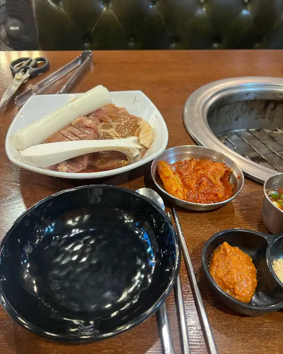 불판 위에 올려진 신선한 고기 한 점과 쌈무