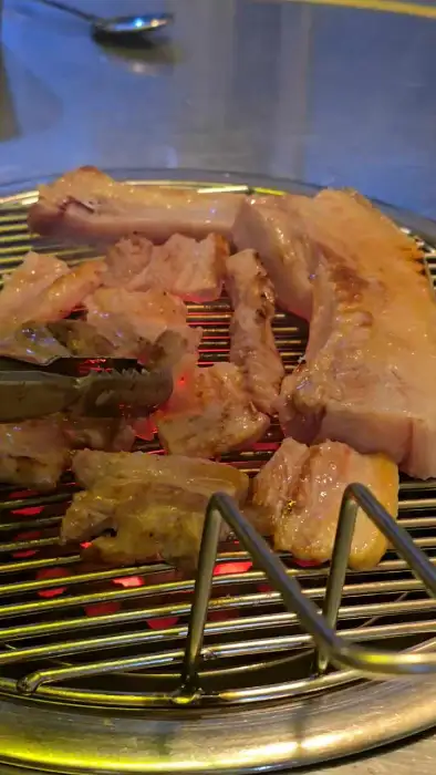 연탄불 위에서 지글지글 구워지고 있는 두툼한 돼지고기 덩어리